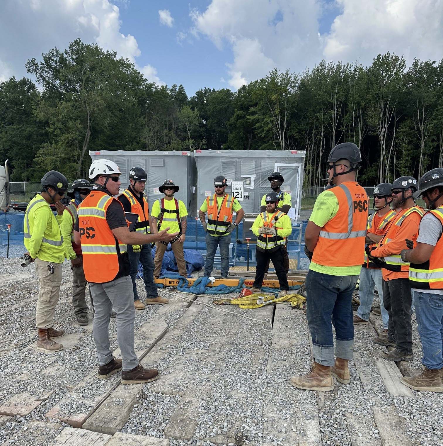 Workers stand in circle for safety briefing.